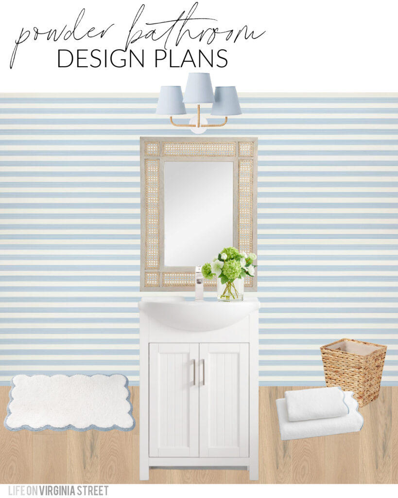 A coastal bathroom design board with spring decor. Features blue and white striped wallpaper, a blue linen sconce with rattan arms, a white vanity, faux viburnum floral arrangement, a seagrass wastebasket, and scalloped bath mat and towels.