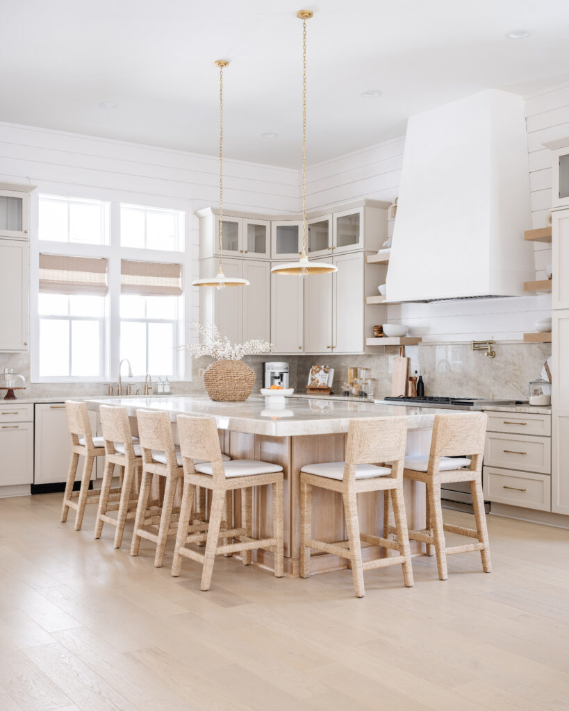 A beautiful coastal modern kitchen featuring white oak hardwood floors, putty colored cabinets, white shiplap walls painted Benjamin Moore Decorator's White, and a white oak island!