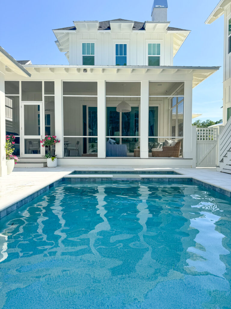 Pebble Tec Signature Matrix Coastal Blue pool photo in a shadow. The white house is painted Sherwin Williams Greek Villa. This post includes all the pool sources including water line tile selection, paver details and more.