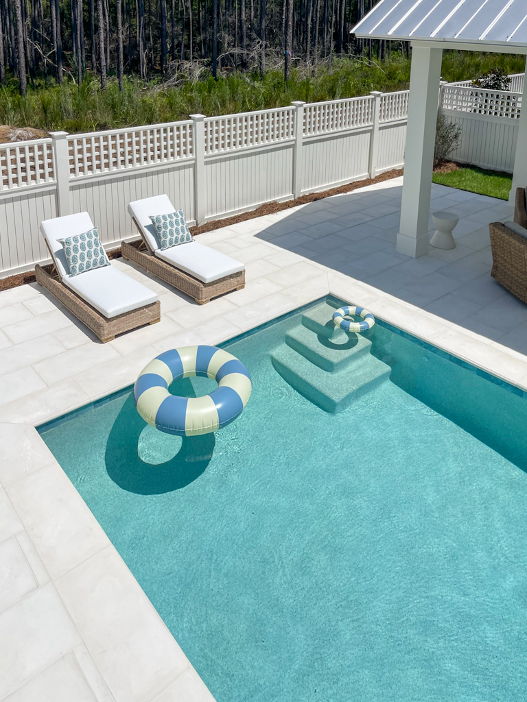 Pebble Tec Signature Matrix Coastal Blue colored pool shown from above. This post includes all the details on this space like the light pavers, pool furniture, water line tile, and more!