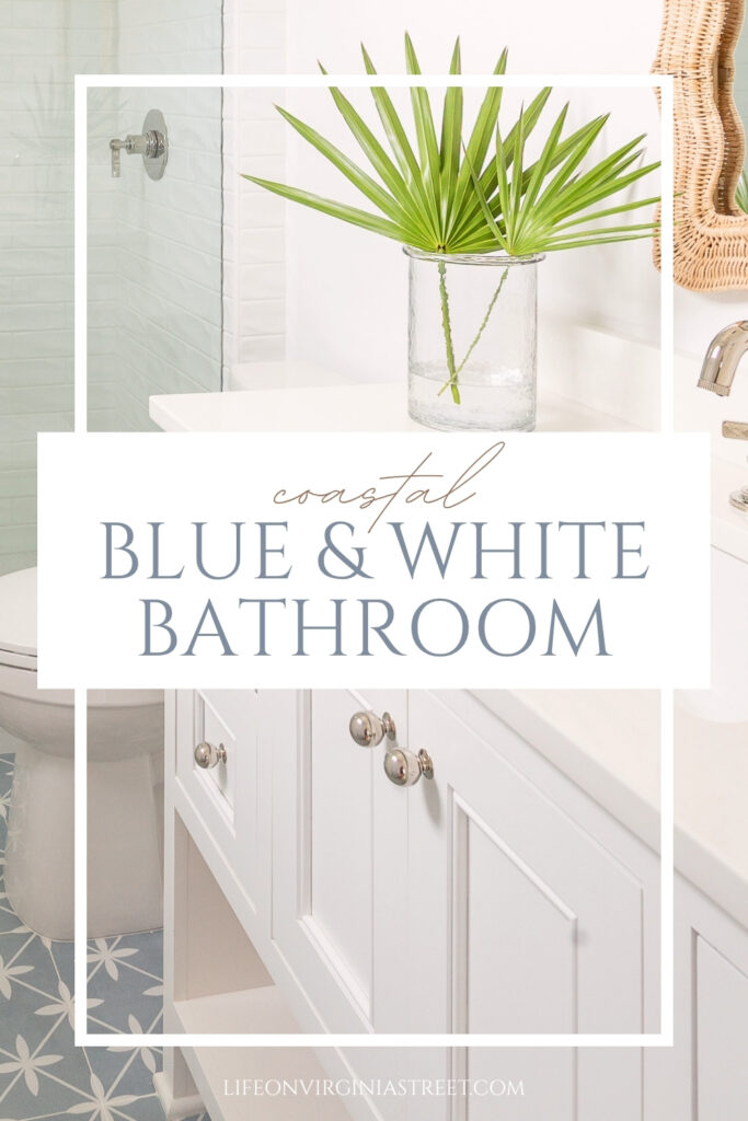A coastal blue and white bathroom tour with blue and white ceramic floor tile, white cabinetry, light blue gray painted door, polished nickel hardware, a woven wicker mirror, and coastal accessories!