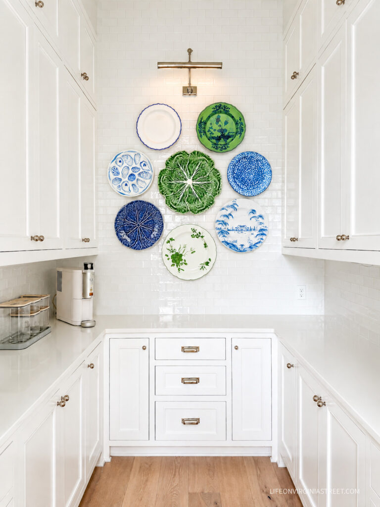 A mock-up of a white pantry and blue and green plate wall over tile.